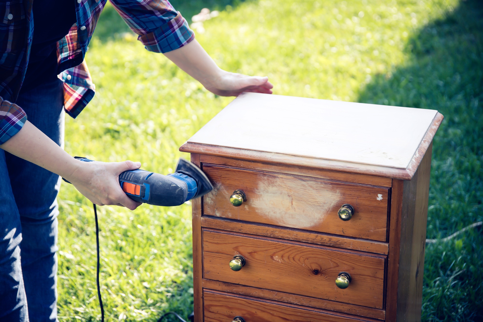 Person using a grinder removes old paint from furniture, restoration of antique furniture